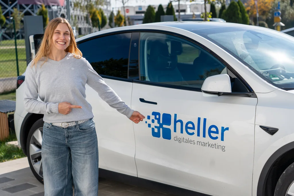 Milena Birkel zeigt auf das Heller-Logo am Firmenwagen