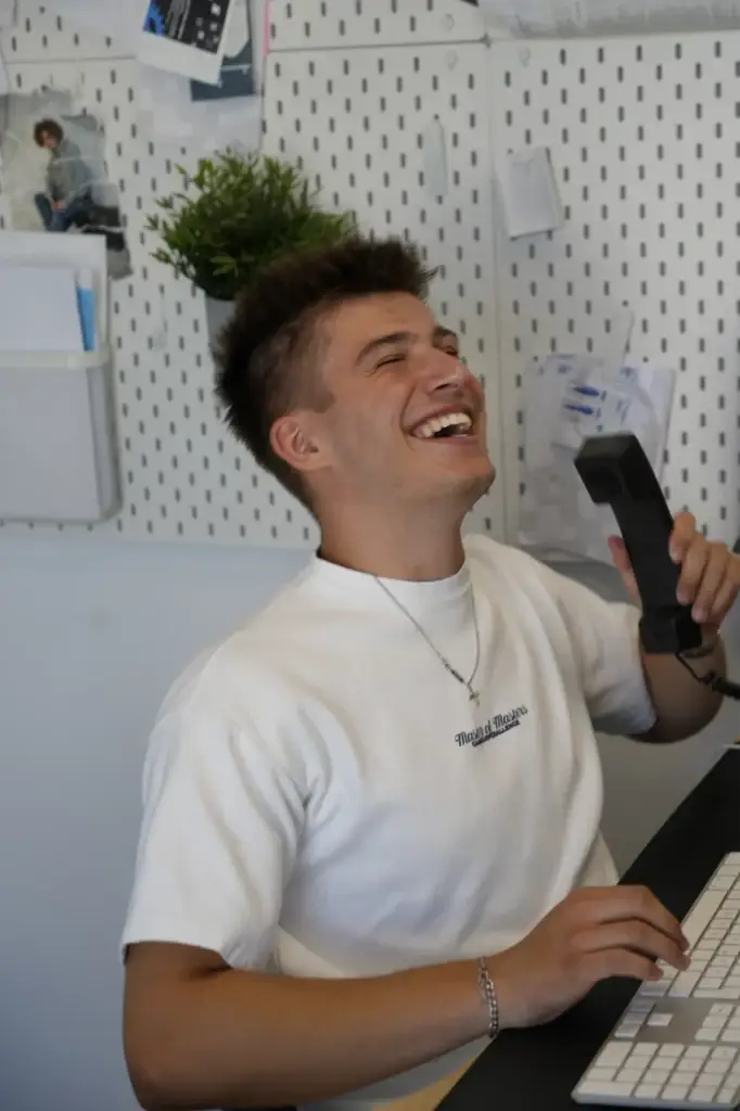 Alessandro Heller lacht am Telefon an seinem Arbeitsplatz