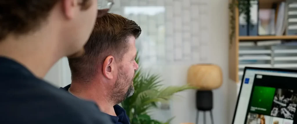 Marco Heller bespricht mit einem Kollegen eine Website am Bildschirm