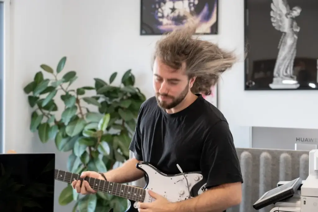 Alex spielt E-Gitarre im Büro